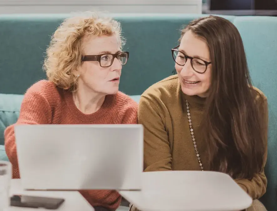 Två kvinnor i kontorsmiljö framför en laptop