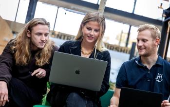 Foto på tre personer med en dator
