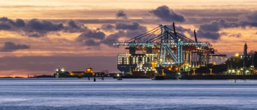Containerfartyg och hamnkranar i kvällsljus med Nya Älvsborgs fästning i bakgrunden