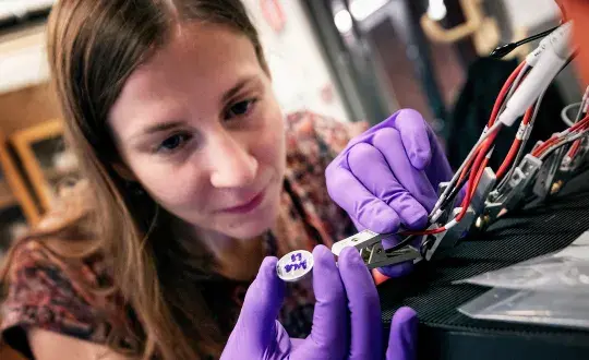 Kvinna med lila handskar fixar med sladdar batteri